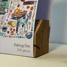 Oak puzzle box stand with 'Baking Day' sleeve on a neutral background