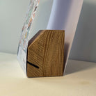 Close-up of an oak puzzle box stand inside a sleeve on a neutral background