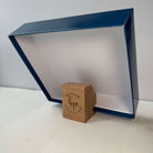 Oak  puzzle box stand with 'Bloom Puzzles' branding holding a blue puzzle box lid.