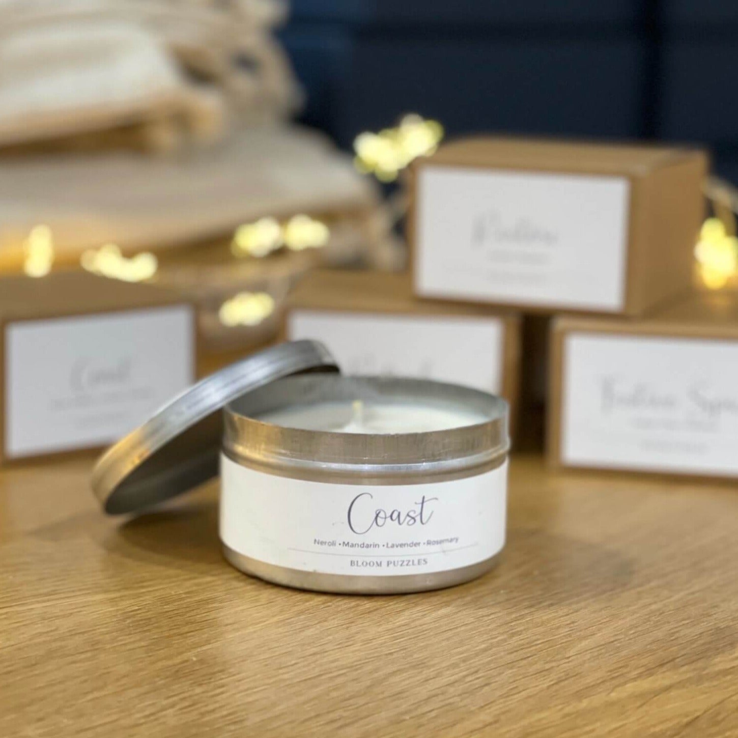 Coast Essential Oil Candle in an aluminium travel tin with boxed candles in the background -  Bloom Puzzles