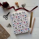 Notebook with garden pattern from The Potting Shed on a white surface with stationery items